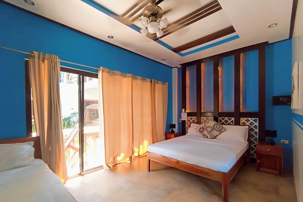 A hotel room with a bed, a nightstand, a ceiling fan, and a view of the outdoors.
