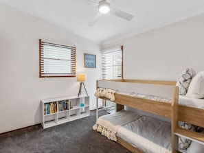 Um quarto com uma cama beliche, uma estante de livros e uma mesa com abajur.