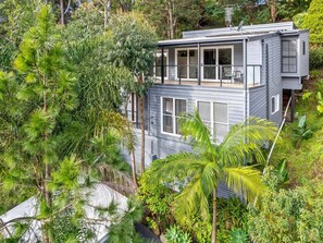A modern two-story house surrounded by lush greenery.