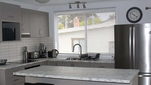 Una cocina moderna con encimera de mármol, electrodomésticos de acero inoxidable y una ventana con persianas.