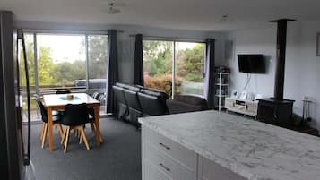 A modern room with a dining table, chairs, a sofa, a TV, and a fireplace.