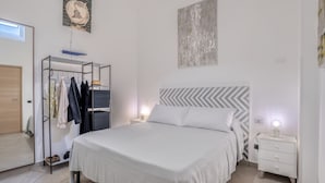 A bedroom with a bed, a wardrobe, a nightstand, and a wall with a chandelier. - 4 Bedrooms Apt in Sorrento Center | location&view (Sorrento)