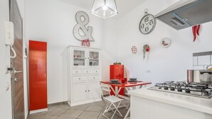 A kitchen with white cabinets, a red refrigerator, a gas stove, and a dining table with chairs. - 4 Bedrooms Apt in Sorrento Center | location&view (Sorrento)