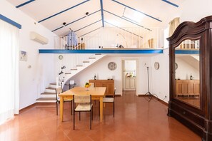 A spacious dining area with a wooden table and chairs, a staircase leading to an upper level, and a large wooden cabinet. - New home with balconies in Sorrento center (Sorrento)