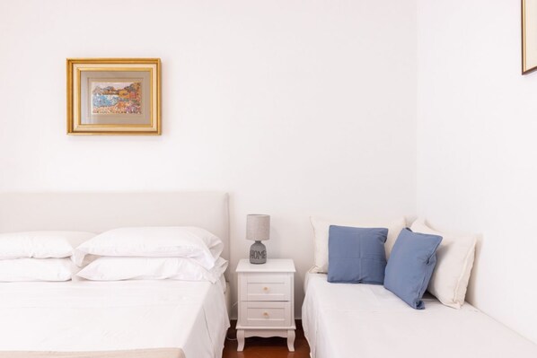 A bedroom with a bed, a nightstand, a lamp, and a framed picture on the wall.