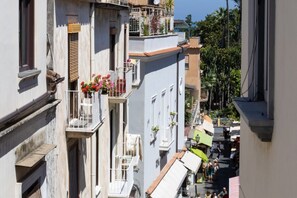 A narrow street with buildings featuring balconies with flower pots and outdoor seating. - New home with balconies in Sorrento center (Sorrento)