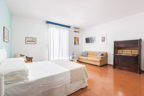 A bedroom with a bed, a sofa, a dresser, and a television on the wall. - New home with balconies in Sorrento center (Sorrento)
