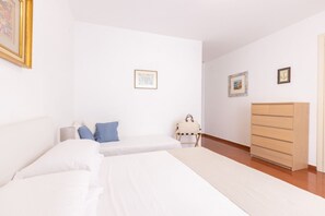 Un dormitorio con dos camas, un aparador de madera y una silla pequeña.