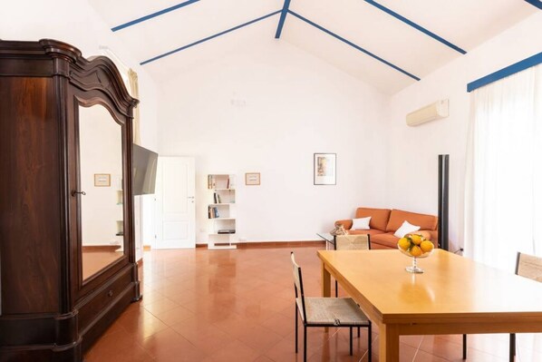 A spacious room with a wooden dining table, a sofa, and a large mirror.