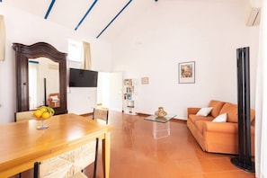 A living room with a wooden dining table, a sofa, a coffee table, and a large mirror.