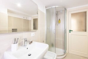 A modern bathroom with a white sink, a glass shower enclosure, and a mirrored wall. - New home with balconies in Sorrento center (Sorrento)