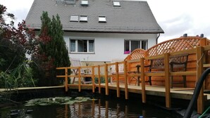 A house with a koi pond, wooden deck, and chairs. - Apartment 'Haus Am Waldrand' with Mountain View, Private Terrace and Wi-Fi (Freital)