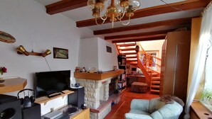 A living room with a fireplace, a TV, and a staircase leading to an upper level. - Apartment 'Haus Am Waldrand' with Mountain View, Private Terrace and Wi-Fi (Freital)