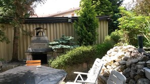 En uteplats med en stenmur, en grill och ett bord med en stol.