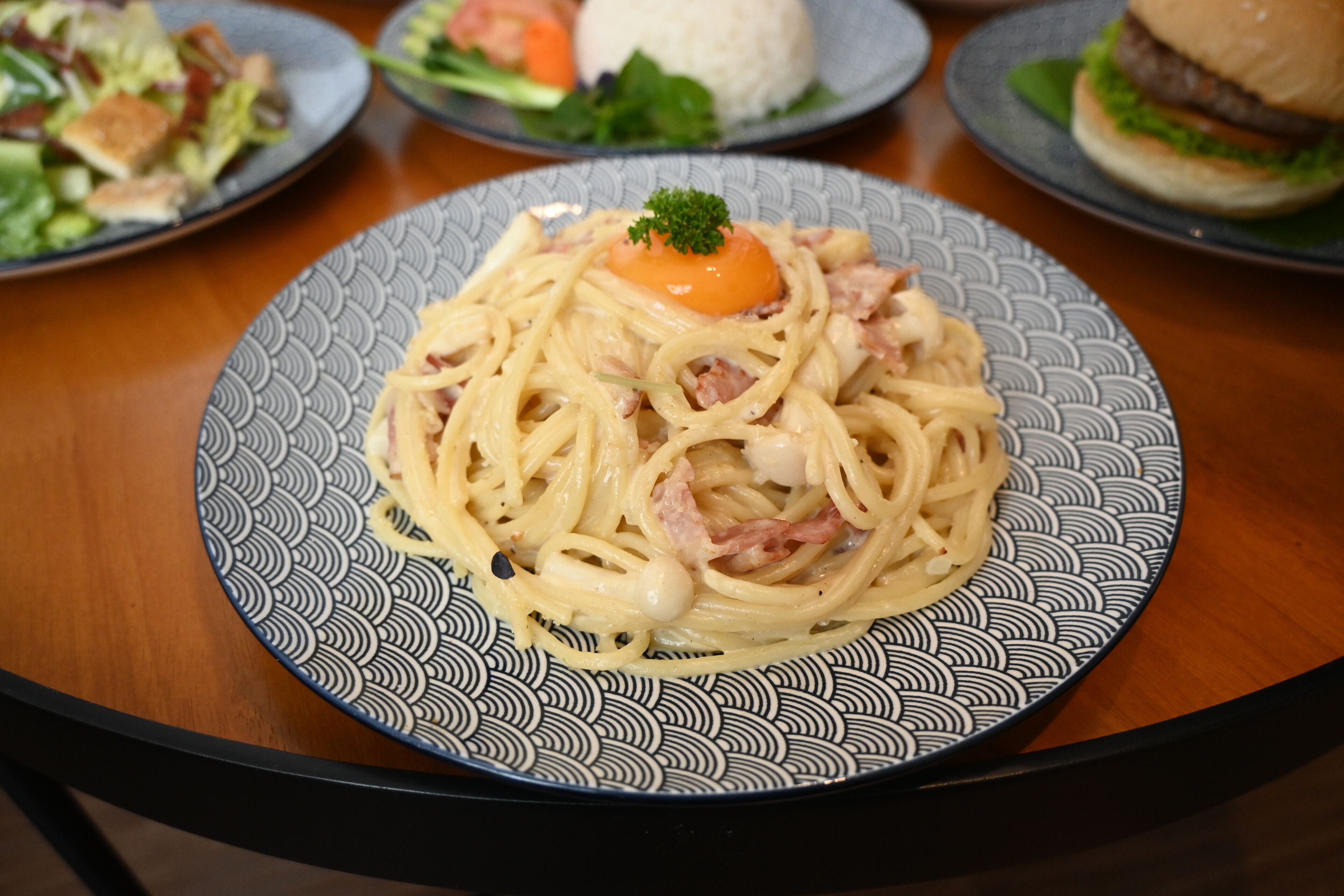 A plate of spaghetti with a garnish, served on a patterned plate.