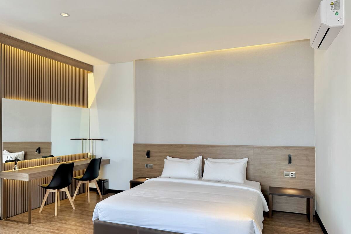 Una habitación de hotel moderna con una cama grande, un escritorio y un espejo.