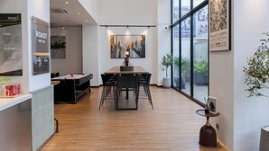 A modern cafe with a wooden table and chairs, a menu board, and a cityscape painting on the wall. - WH Hotel 310  (Phnom Penh)