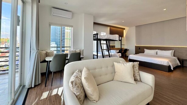 A modern hotel room with a sofa, a bed, a desk, and a bunk bed. - WH Hotel 310  (Phnom Penh)