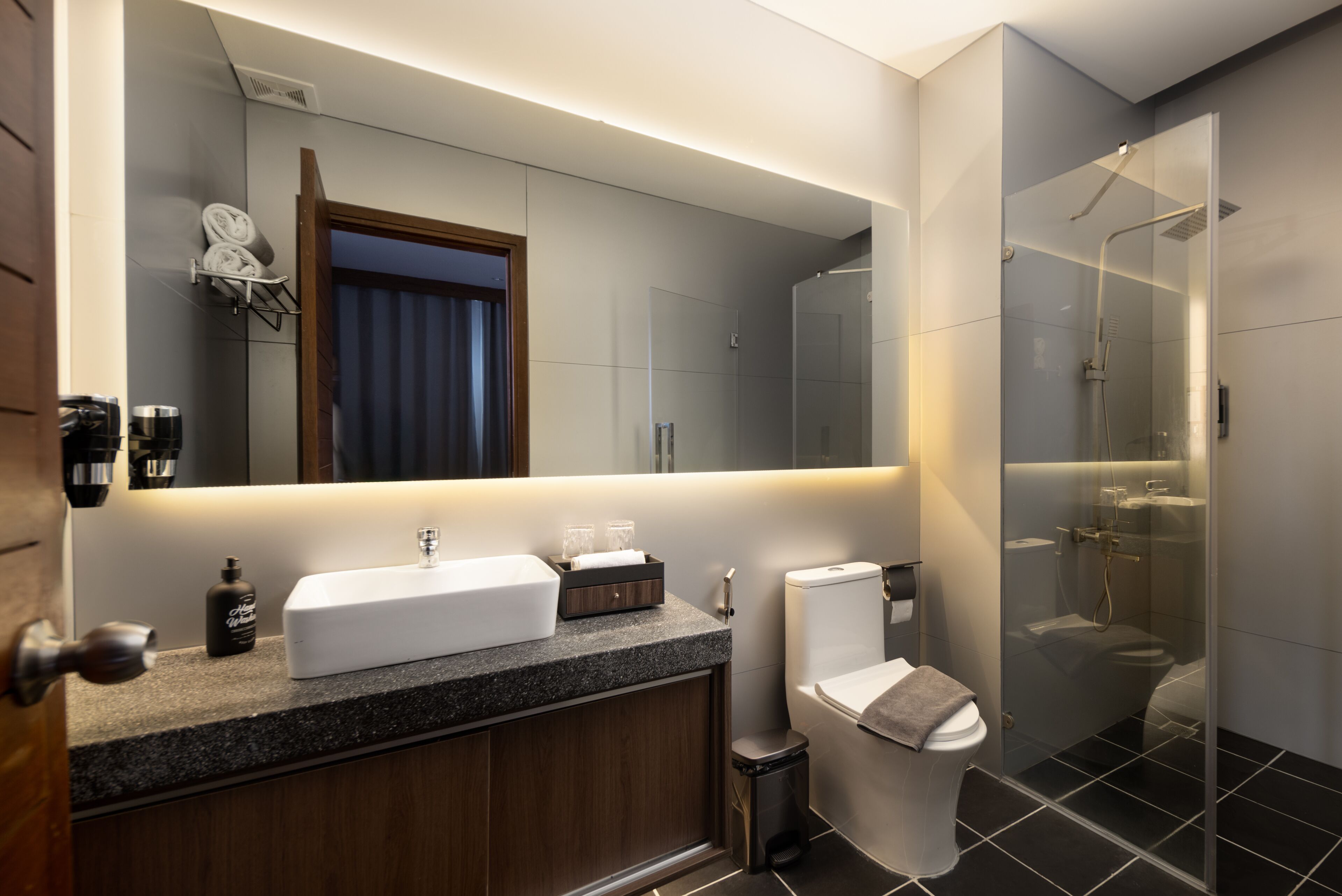 Ein modernes Badezimmer mit großem Spiegel, Waschbecken, Toilette und einer Duschkabine.