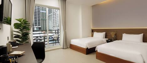 A hotel room with two beds, a desk, a chair, and a large window with a view of tall buildings.