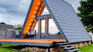 Ett modernt hus i form av en triangel, med ett sluttande tak, stora fönster och en träveranda.