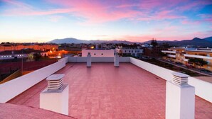 A rooftop terrace with a view of a cityscape and mountains in the distance. - Aparthotel Autosole (Estepona)