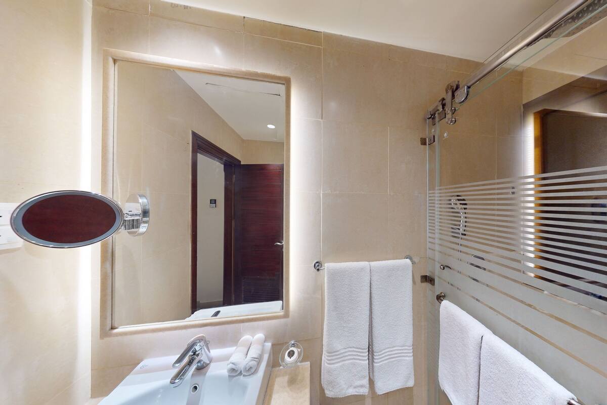 A modern bathroom with a large mirror, a sink, and a shower area.