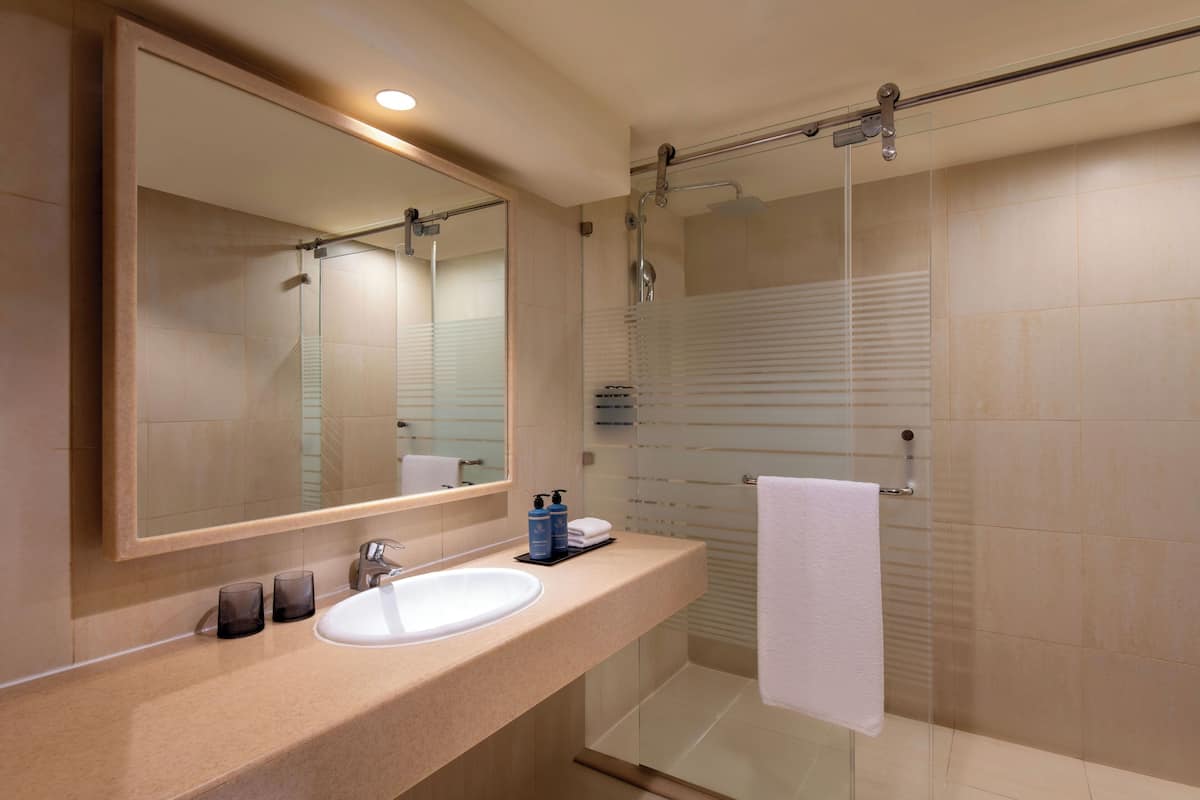 A modern bathroom with a large mirror, a sink, and a glass-enclosed shower area.