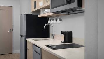 A modern kitchen with a built-in dishwasher, a black refrigerator, a microwave, and a coffee machine.