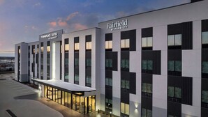 A modern hotel exterior with "Fairfield by Marriott" signage, a covered outdoor seating area, and a parking lot. - TownePlace Suites by Marriott Paris (Paris)