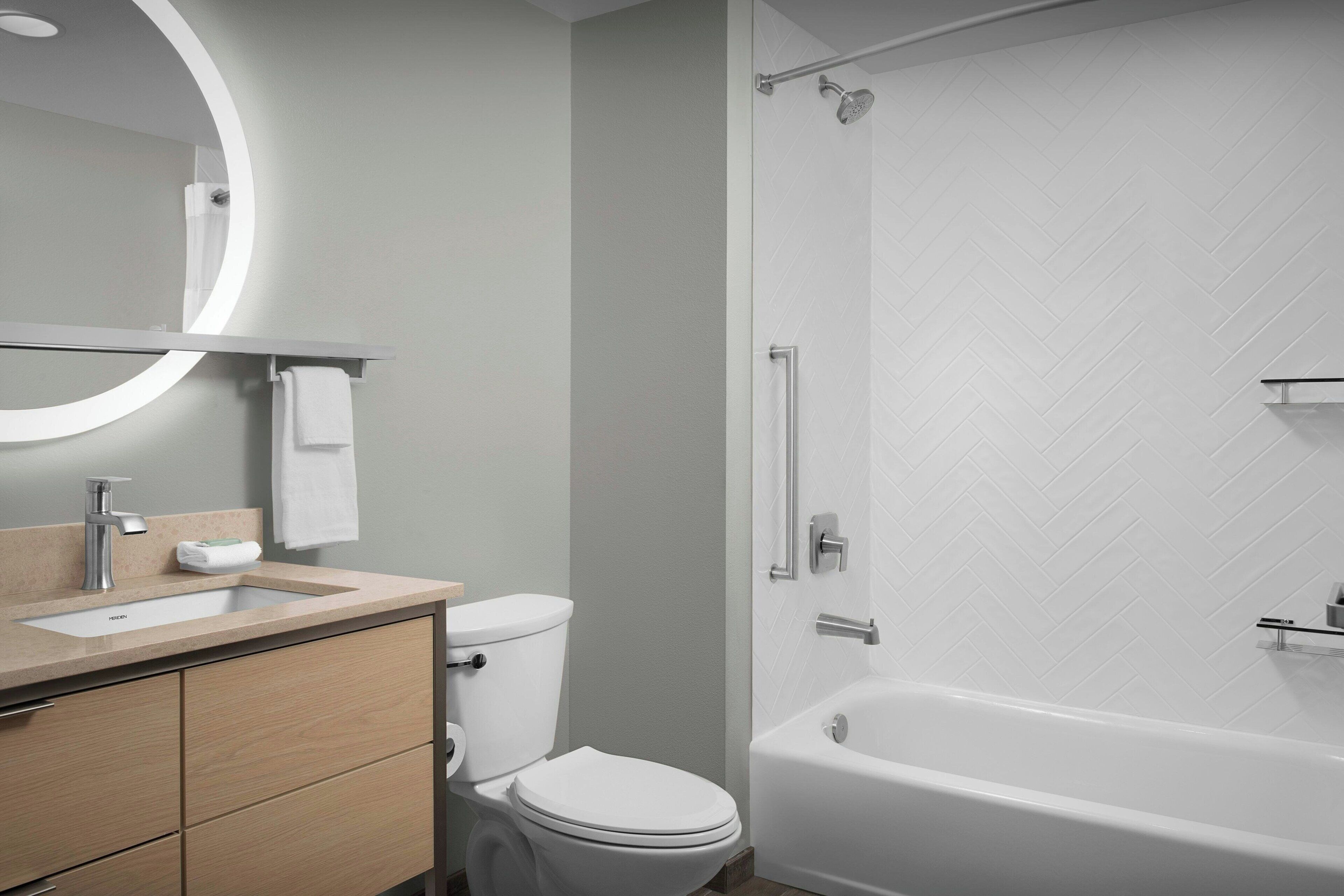 A modern bathroom with a sink, toilet, and bathtub.