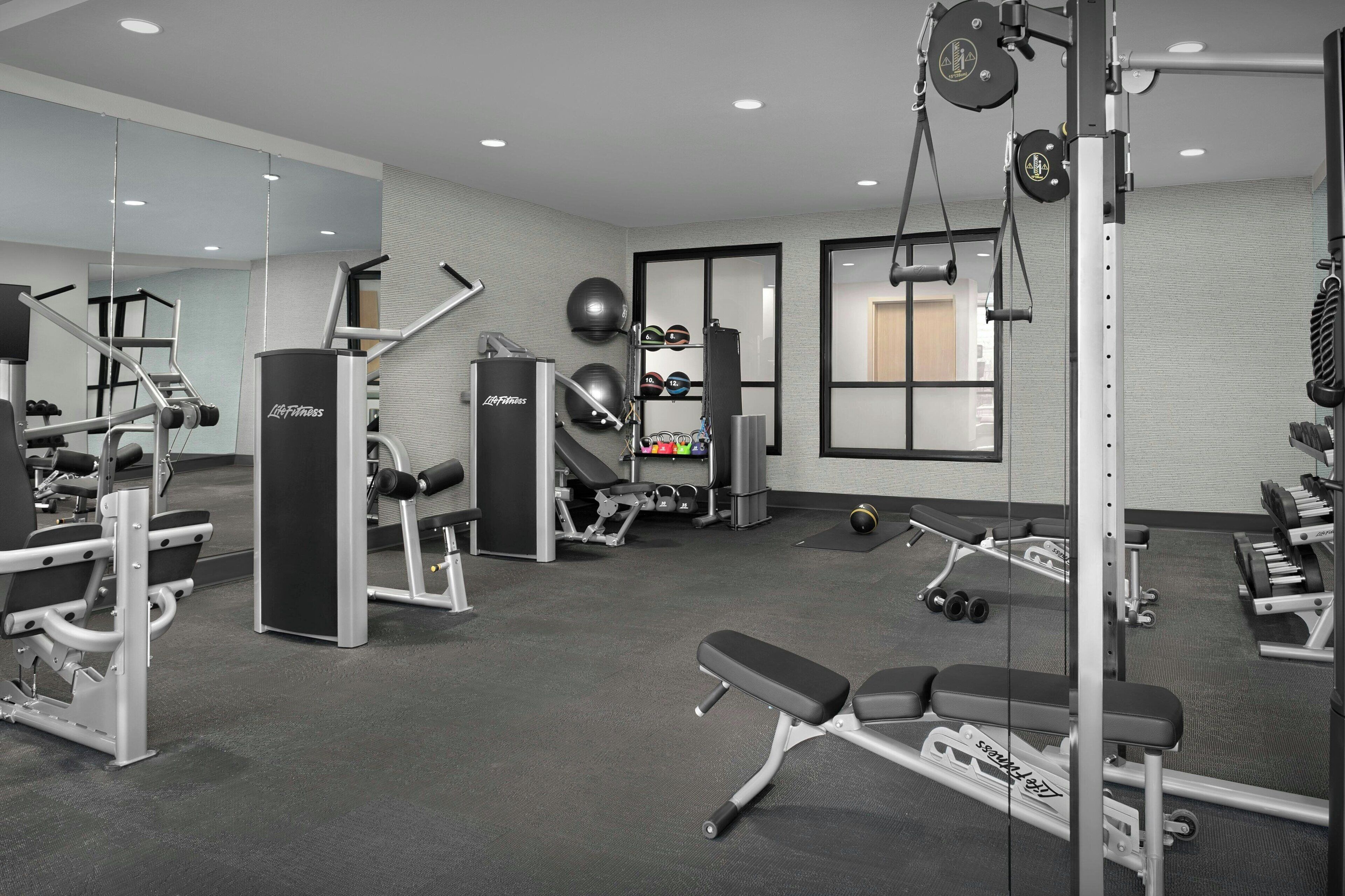 Een moderne sportschool met diverse fitnessapparaten, waaronder krachttrainers, losse gewichten en cardio-apparatuur.