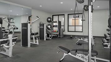 Een moderne sportschool met diverse fitnessapparaten, waaronder krachttrainers, losse gewichten en cardio-apparatuur.