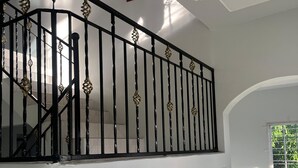 A staircase with black balusters and a white railing, leading to an upper floor. - The Retreat (Lyssons)