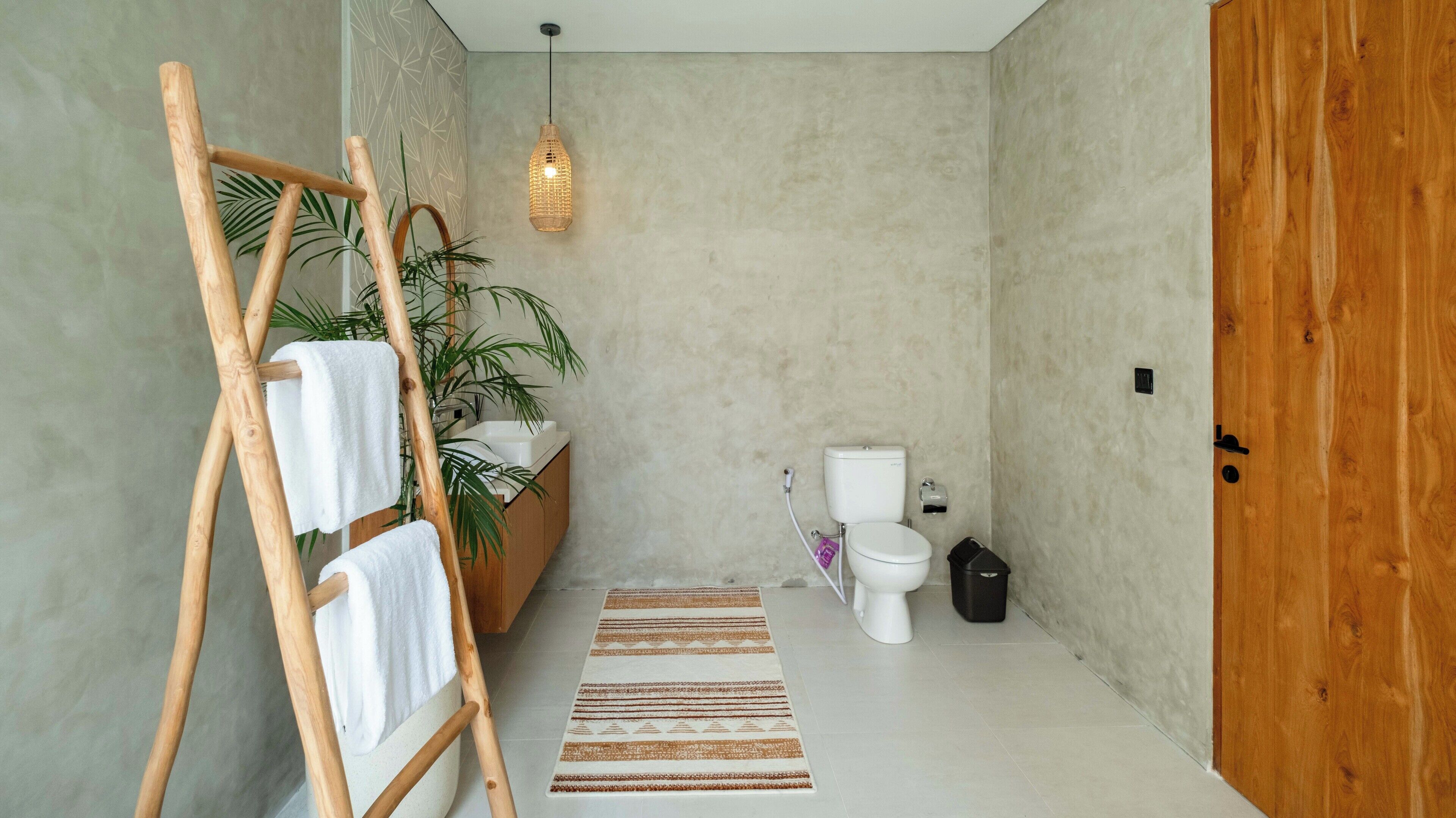 A bathroom with a wooden ladder, a sink, a toilet, a hanging light fixture, and a wooden door.