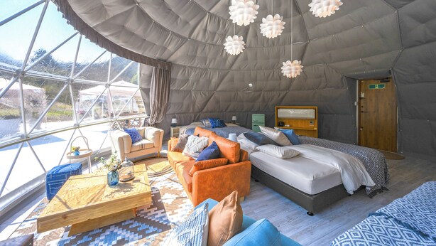 Ein geräumiges Zimmer mit einem großen Bett, einer Couch und einem Holztisch. Ein Fenster bietet einen Ausblick ins Freie.