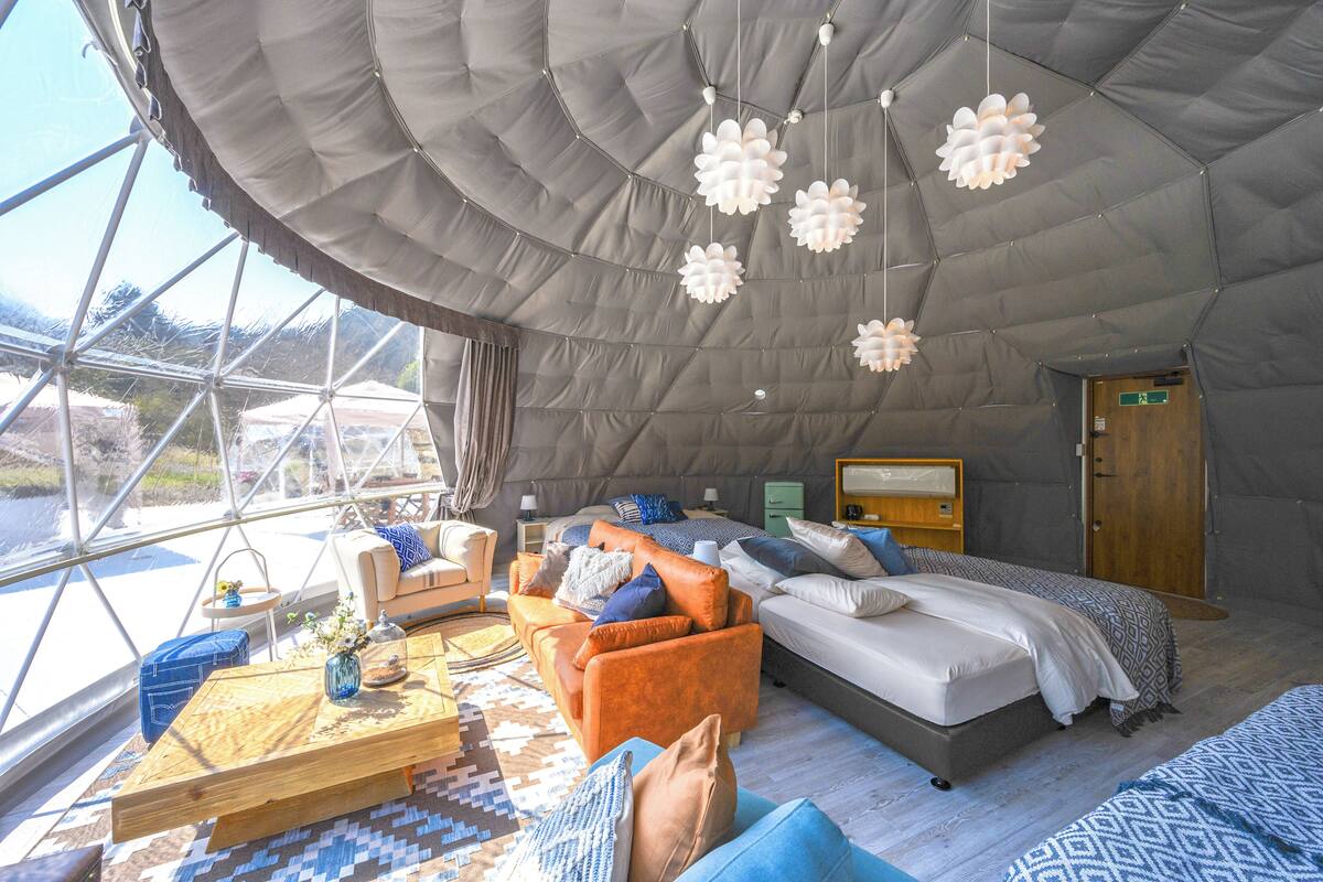 Ein geräumiges Zimmer mit einem großen Bett, einer Couch und einem Holztisch. Ein Fenster bietet einen Ausblick ins Freie.