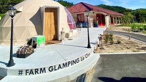 Ein Glampingplatz auf einem Bauernhof mit einem großen Zelt, einem Empfangsbereich und einem Gebäude mit rotem Dach.