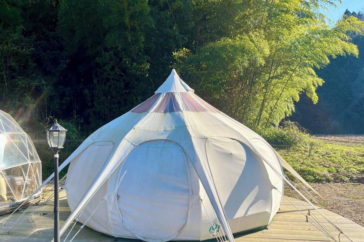 Ein kuppelähnliches Zelt mit spitzer Kuppel, auf einer Holzdielen terrasse gelegen, mit einem Lampenpfosten in der Nähe.