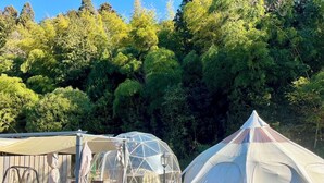 Ein Campingplatz mit mehreren Zelten und einem überdachten Sitzbereich.