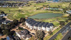 An aerial view of a residential area with houses, a golf course, and a large body of water. - StayAU 3BR Deluxe Family Loft Point Cook (Point Cook)