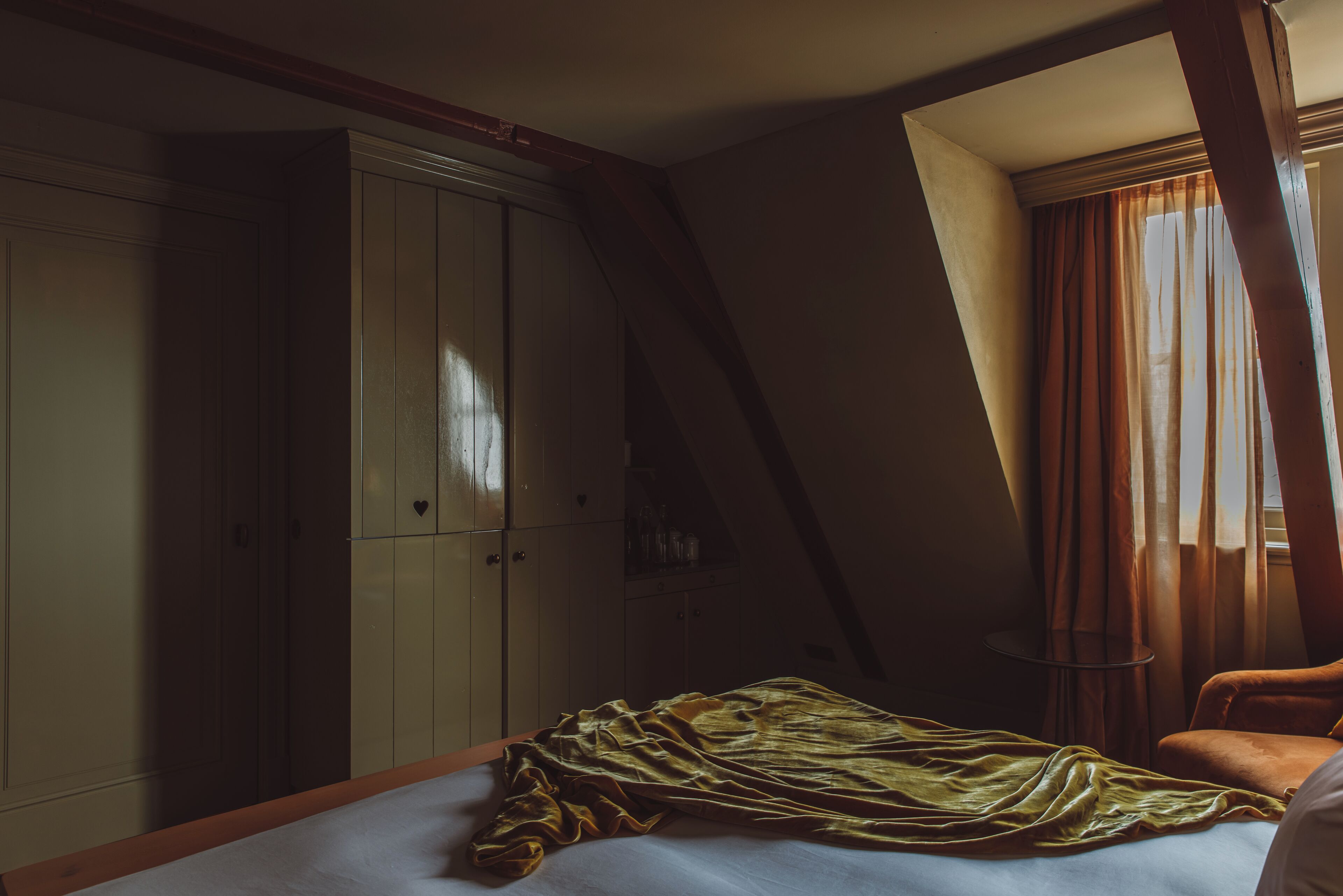 Ein Schlafzimmer mit einem Bett, einem Kleiderschrank und einem Fenster mit Vorhängen.