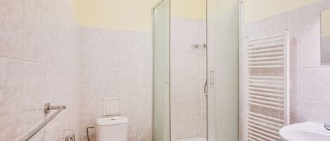 A bathroom with a glass-enclosed shower, a toilet, a sink, and a towel rack.
