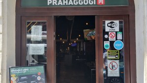 De ingang van restaurant The Real Korean BBQ Prahaggogi met een menubord buiten.