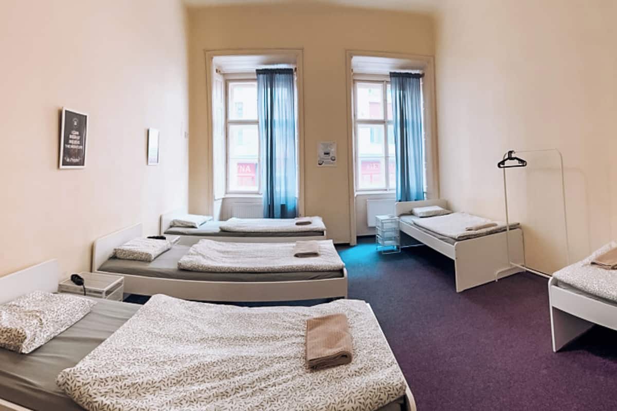 A hotel room with two single beds, a desk, a chair, and a wardrobe.