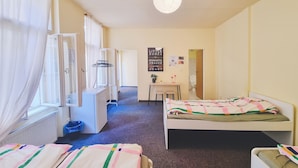 Een slaapkamer met twee bedden, een bureau, een stoel en een radiator.