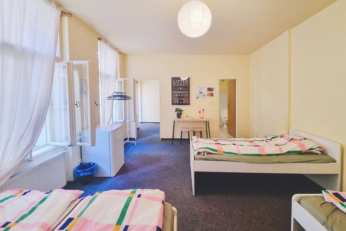 A bedroom with two beds, a desk, a chair, and a radiator.