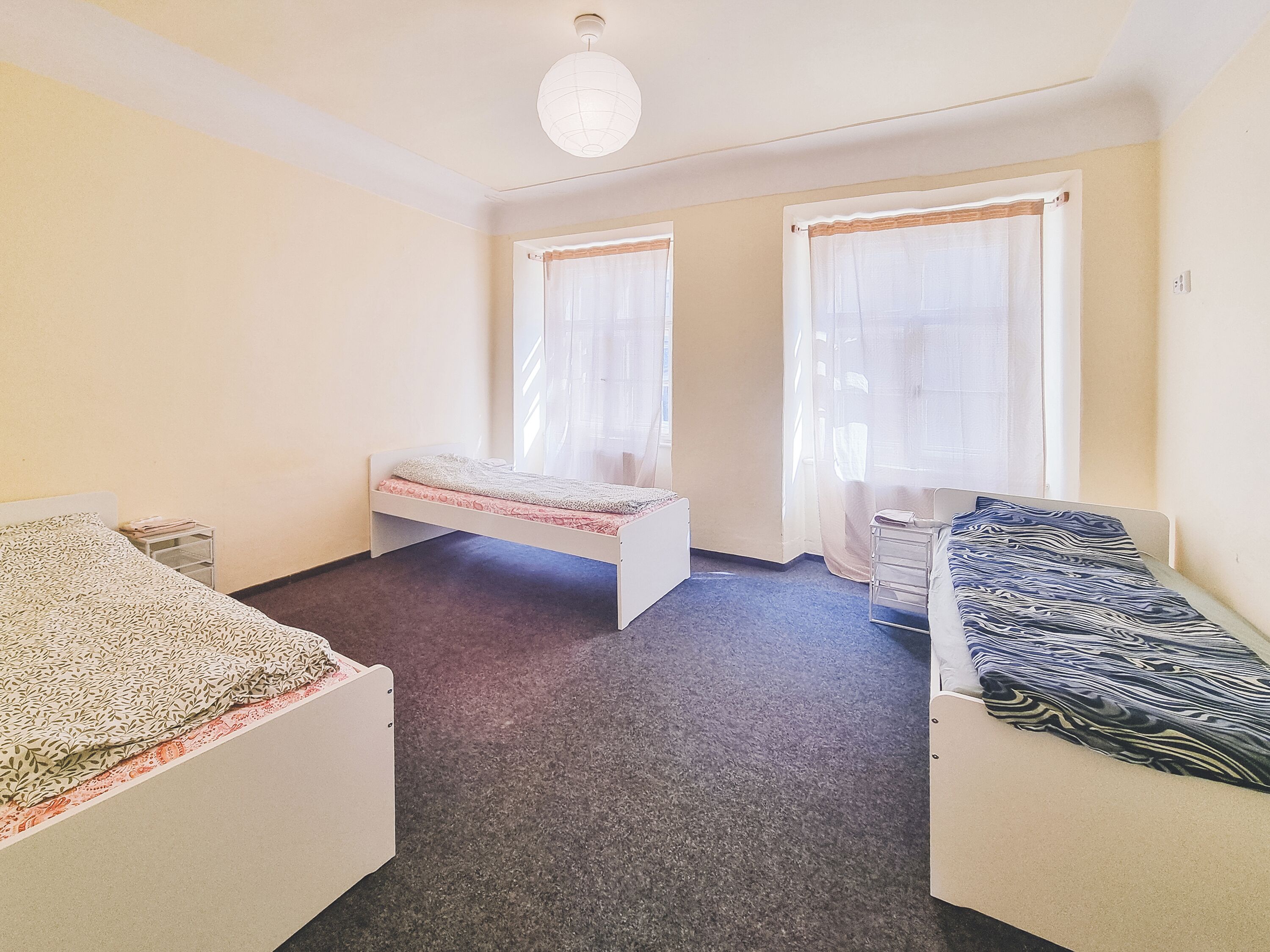 Una habitación con dos camas individuales, una mesita y una silla.