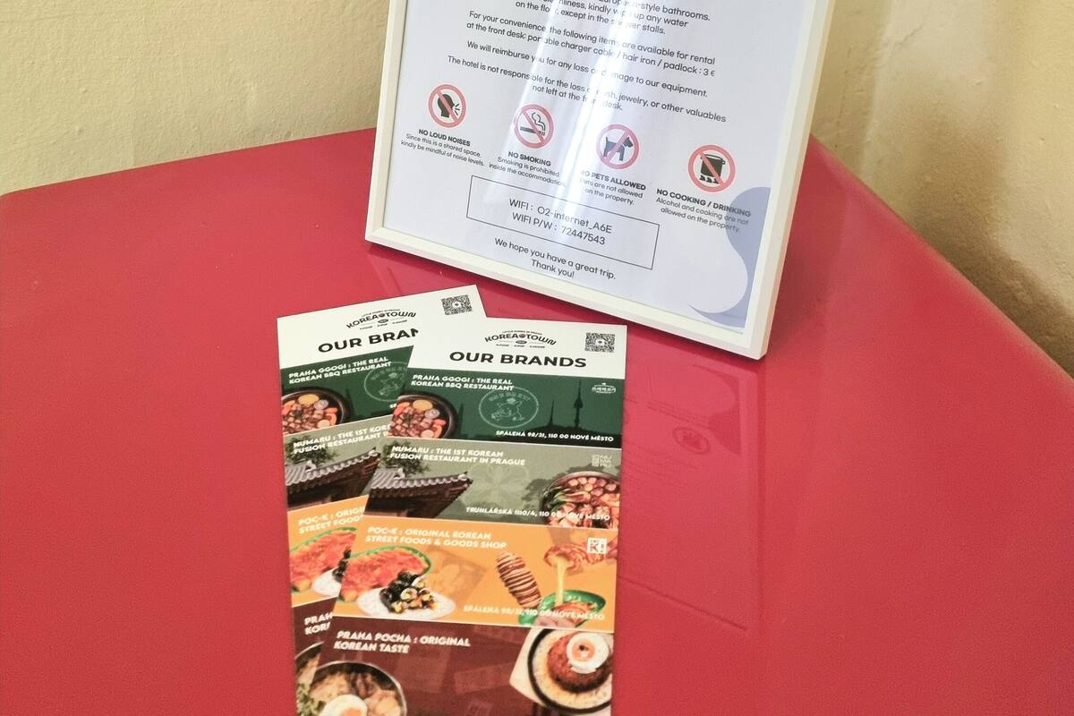 A signboard with check-in and check-out times, luggage storage information, and a list of amenities like towels, a hair dryer, and a table.
