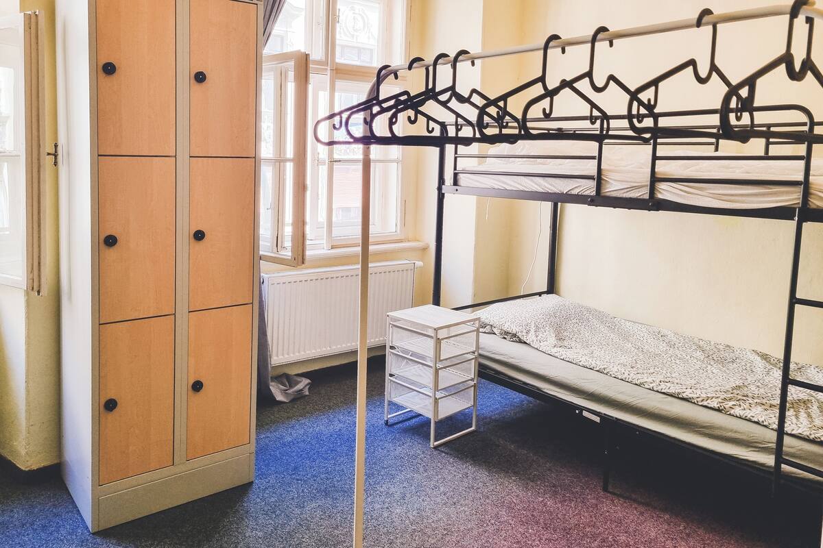 A dormitory room with bunk beds, a wardrobe, and a radiator.